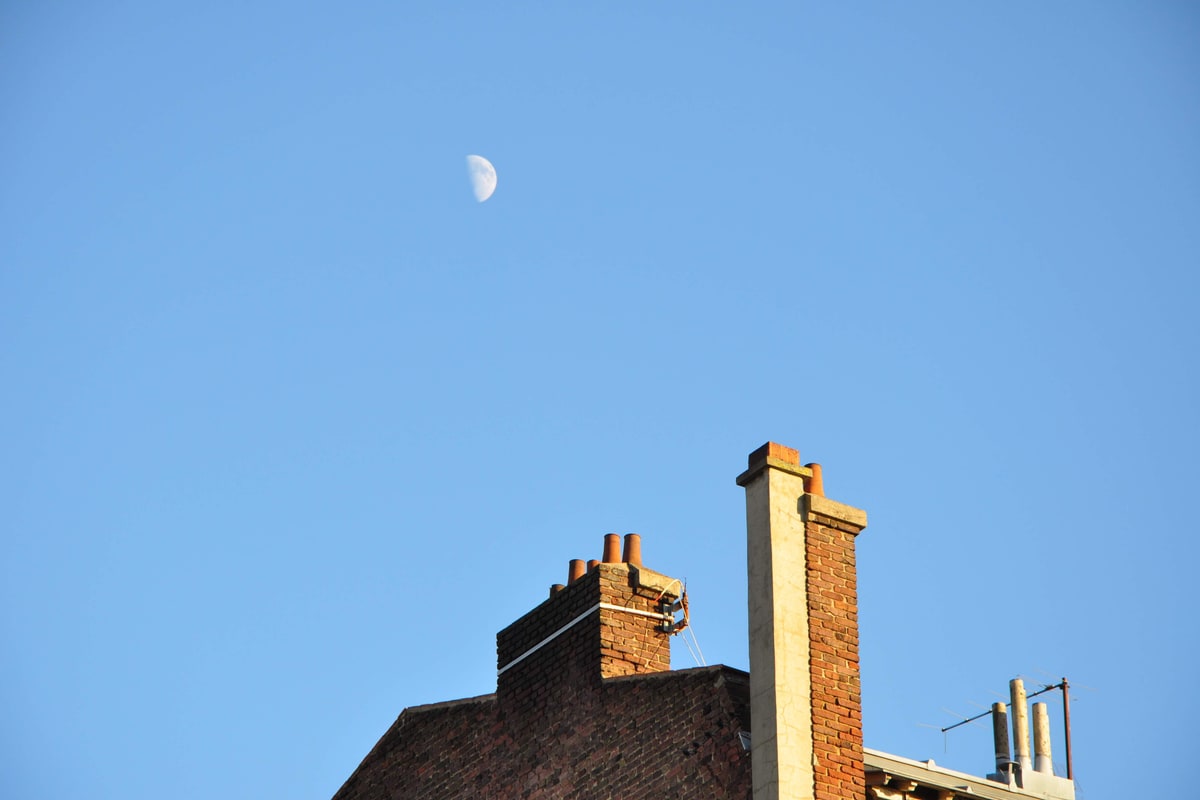 Luna pe cerul albastru în timpul zilei, alături de un coș de fum, fotografie din 2009