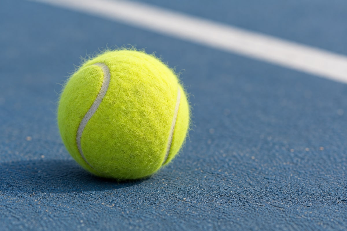 Ilustrație AI cu o minge de tenis galben-verzuie, cu fibrele învelișului vizibile, pe un teren albastru